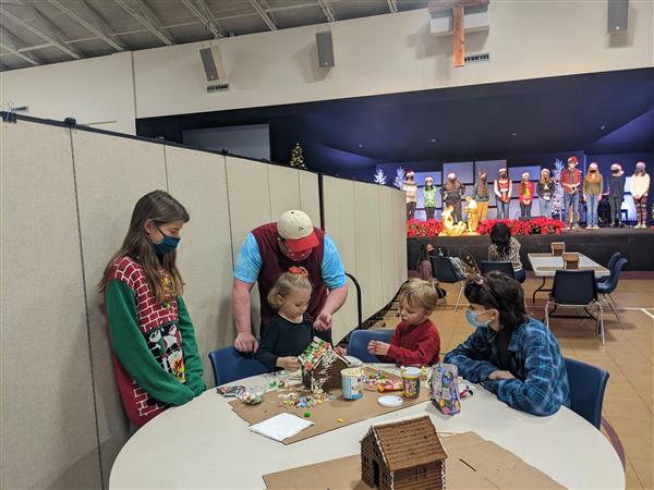 Northern high school students performing on stage for community event in the background, as others do crafts at table